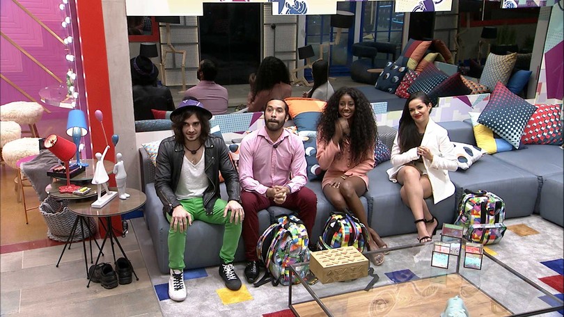 Juliette, Fiuk, Thaís e Arthur do BBB 21 sentados em um sofá em uma sala decorada com almofadas coloridas.