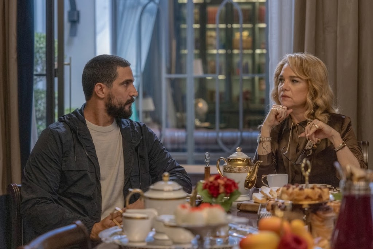 Pilar e Heitor, juntos, em uma mesa de jantar